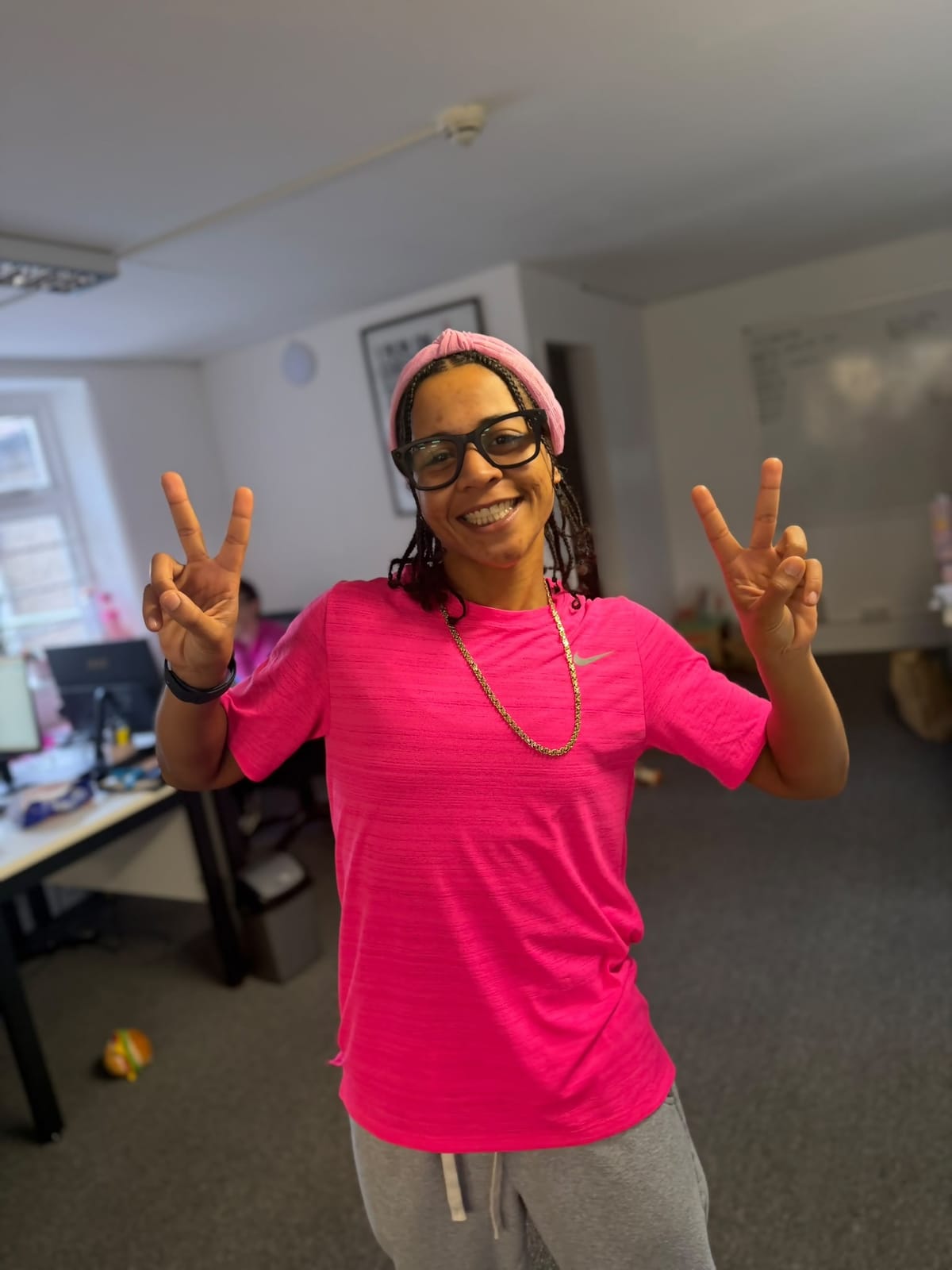 FT Recruitment team member in a bright pink t-shirt and pink headband giving two peace signs