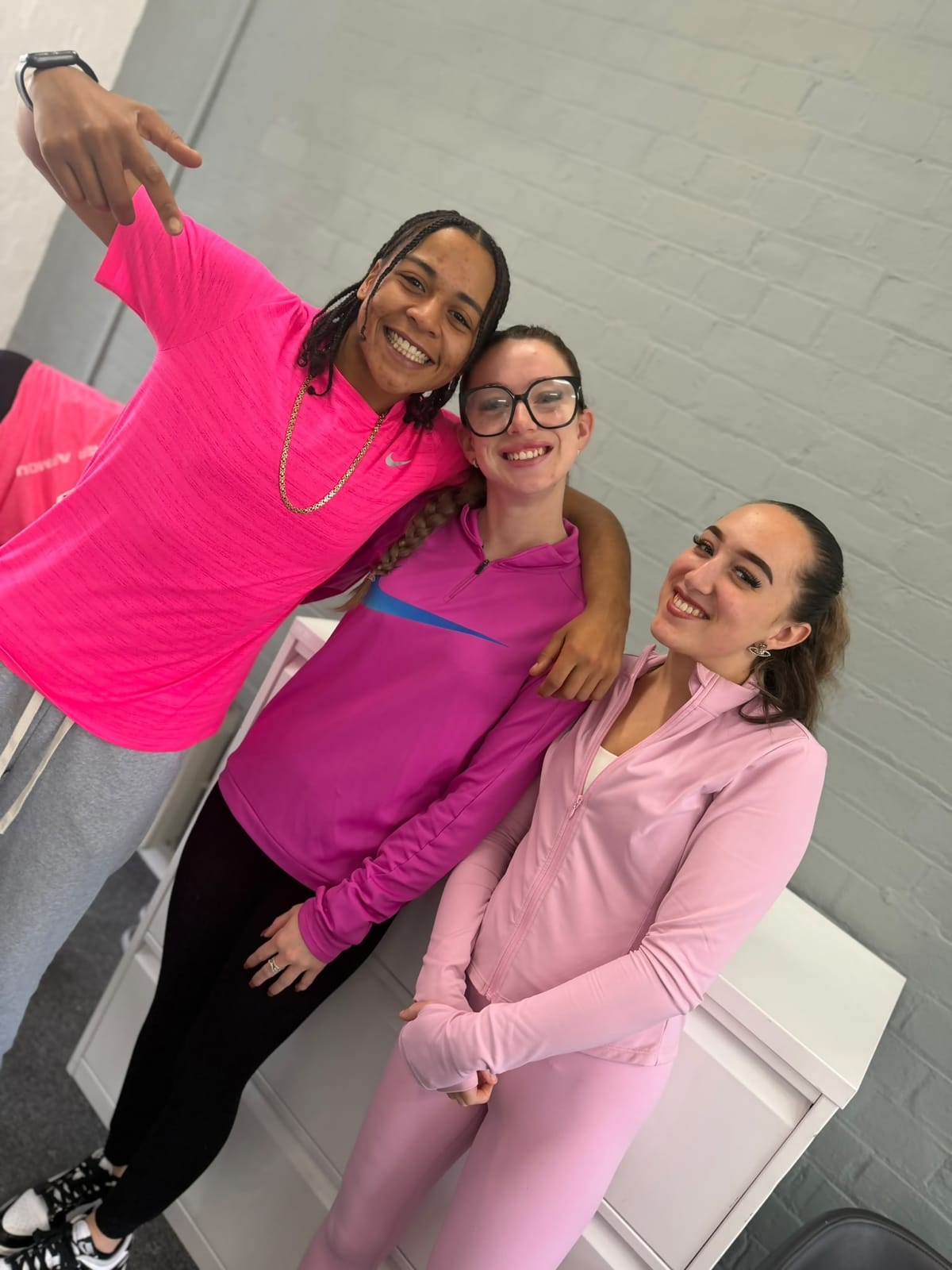 Three FT Recruitment team members in pink tops smiling in the office on Pink Friday