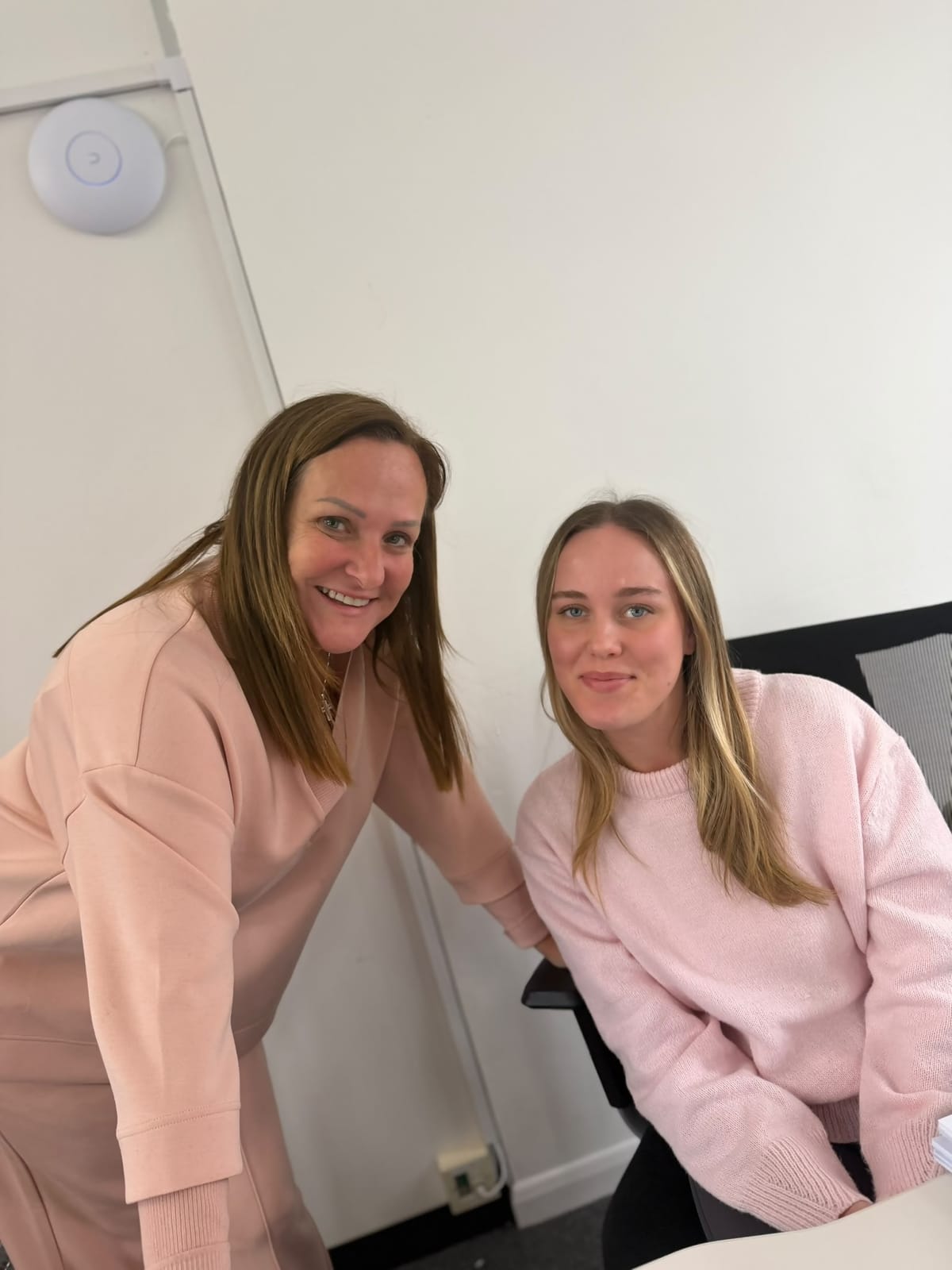 Two FT Recruitment colleagues in pink jumpers at a desk