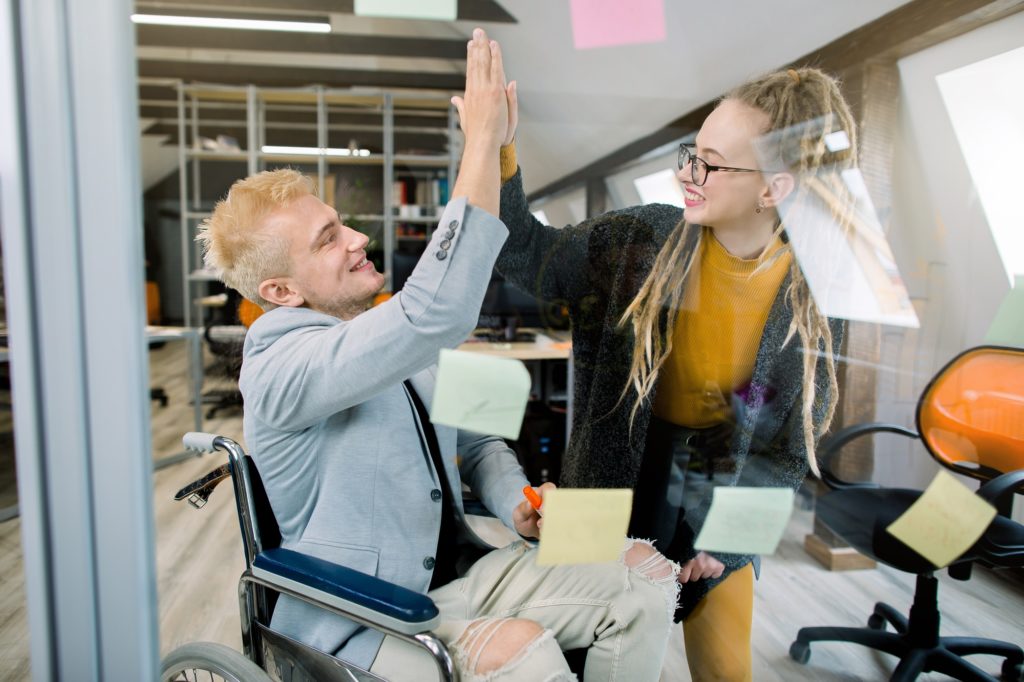 Business concept, successful disabled people at work. Happy successful young man in wheelchair